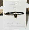 Black beaded bracelet with a gold leo zodiac charm on a Santore branded card.