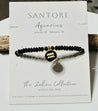 Black beaded bracelet aquarius zodiac charm with gold accents on a Santore branded card.