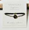 Black beaded bracelet with gold capricorn symbol charm on a Santore branded card.